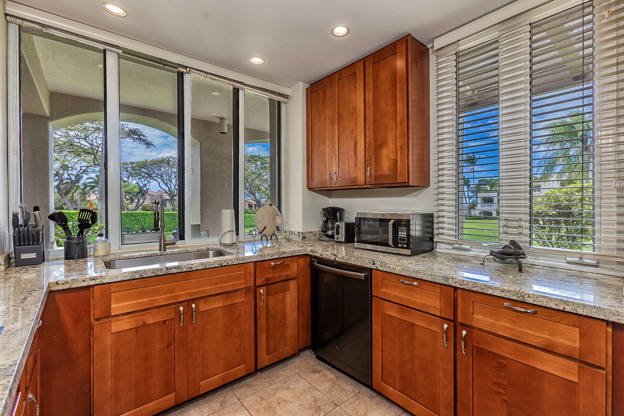 Your fully-equipped kitchen blends warm wood cabinetry with granite counters, while sunlight streams through surrounding windows. Cook comfortably or simply enjoy morning coffee overlooking lush tropical greenery.
