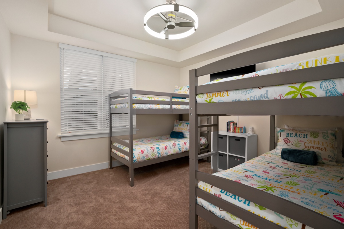 Beach-themed bunk room with cheerful bedding and plenty of storage space.