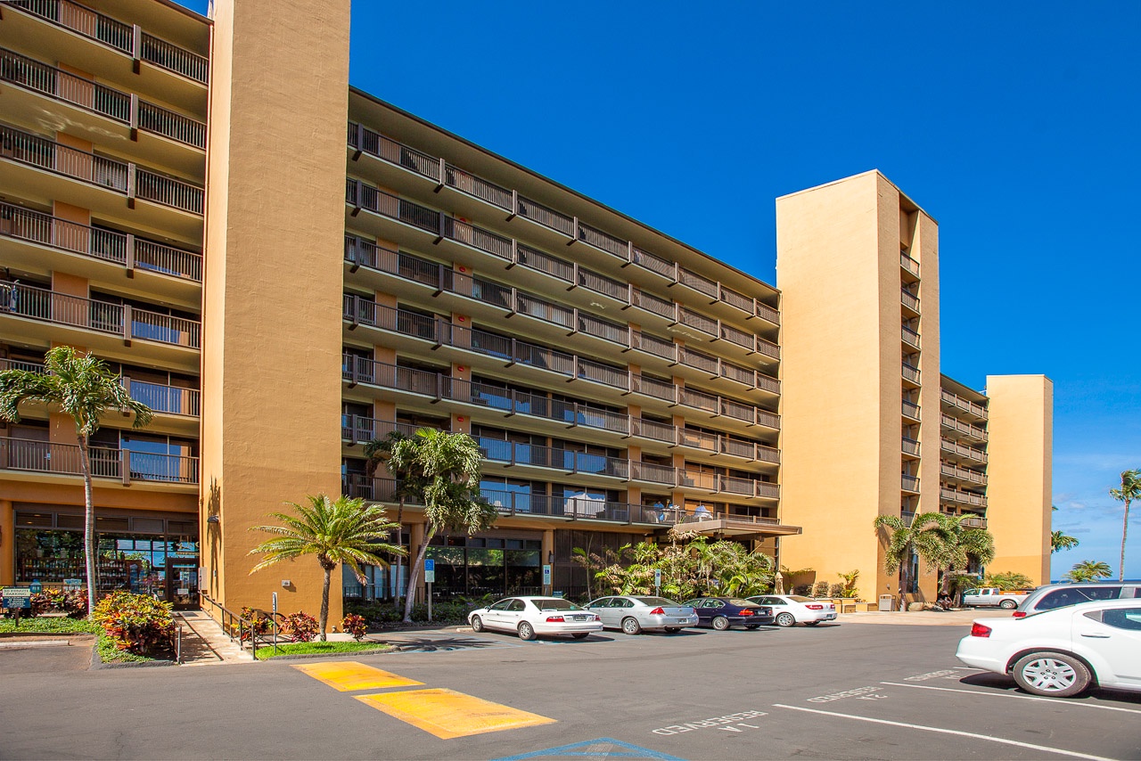 Modern hotel complex with convenient parking and tropical landscaping under clear blue skies.