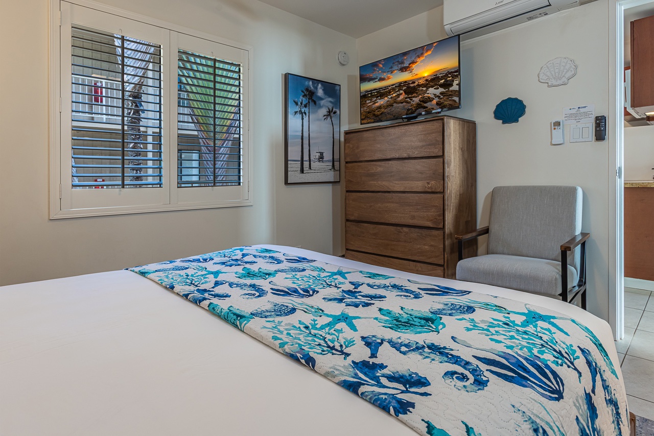 Drift into peaceful sleep on your comfortable queen bed, surrounded by coastal artwork and a warm armchair for quiet moments.