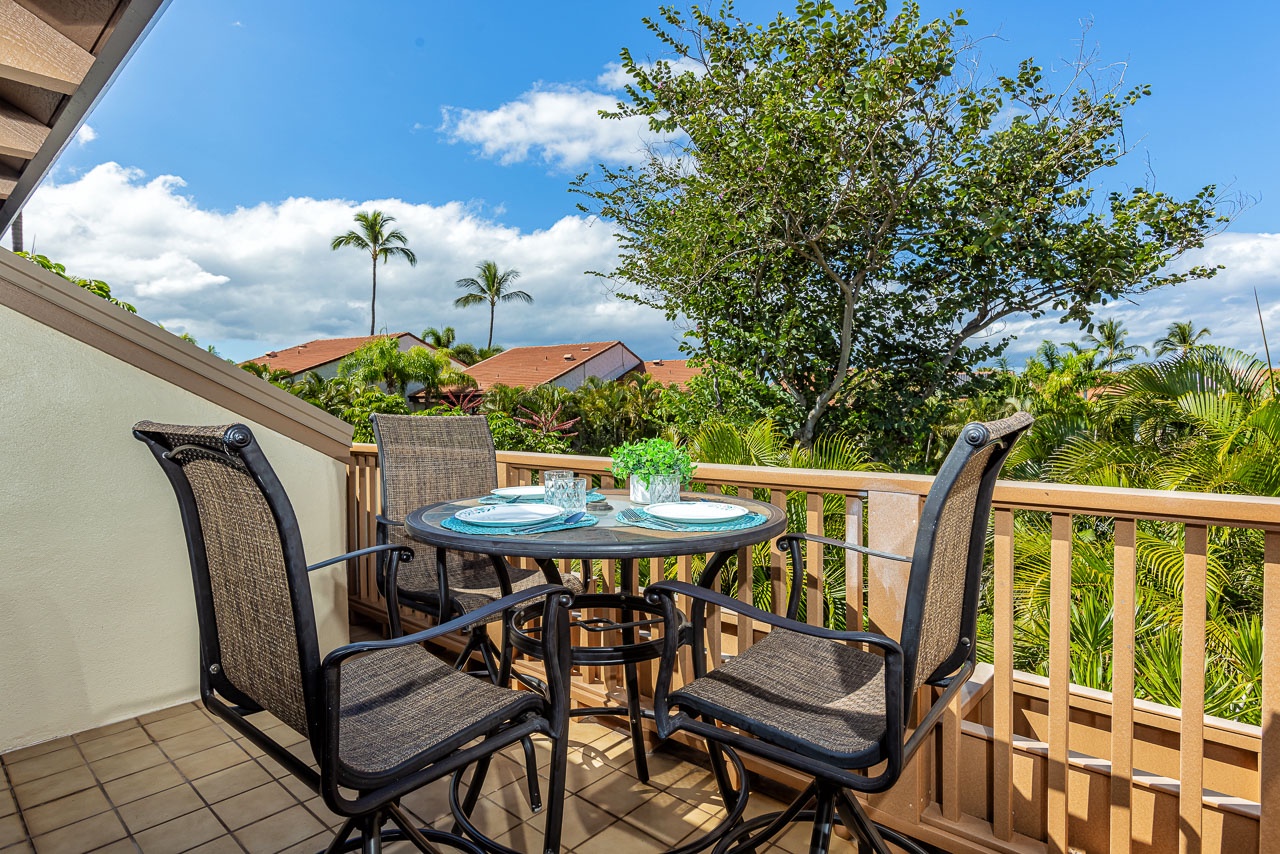 Relax on your private balcony with lush tropical views surrounding you. Enjoy morning coffee at the outdoor table while palm trees sway and the sunny sky frames your peaceful retreat.