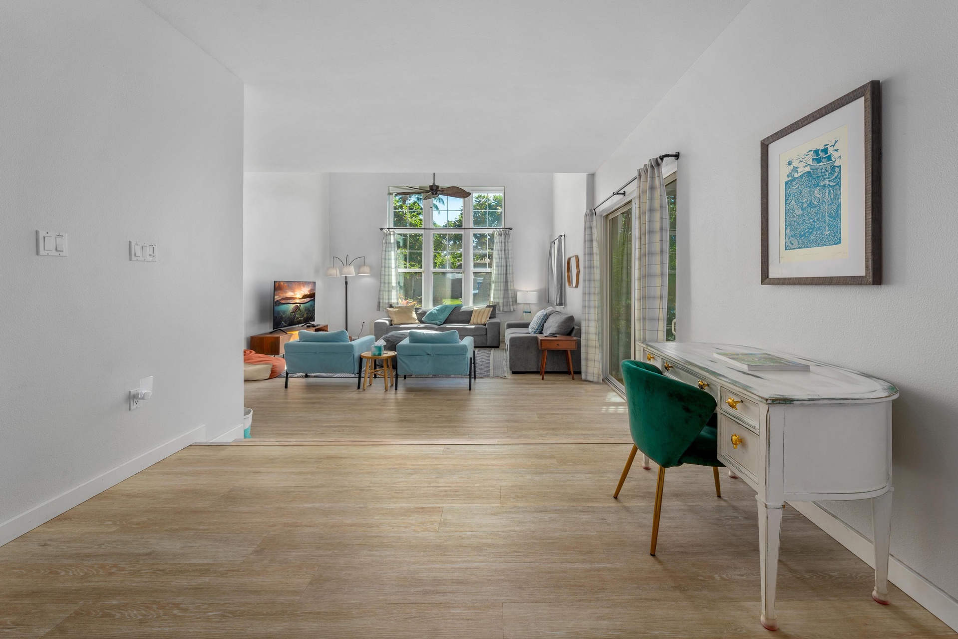 Relax in your bright, open living space with stylish turquoise accents, warm wood floors, and a dedicated workspace.