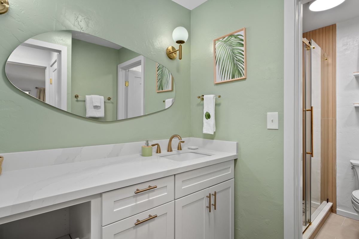 Beautifully refreshed bathroom, where calming sage walls and gold accents create a spa-like retreat.