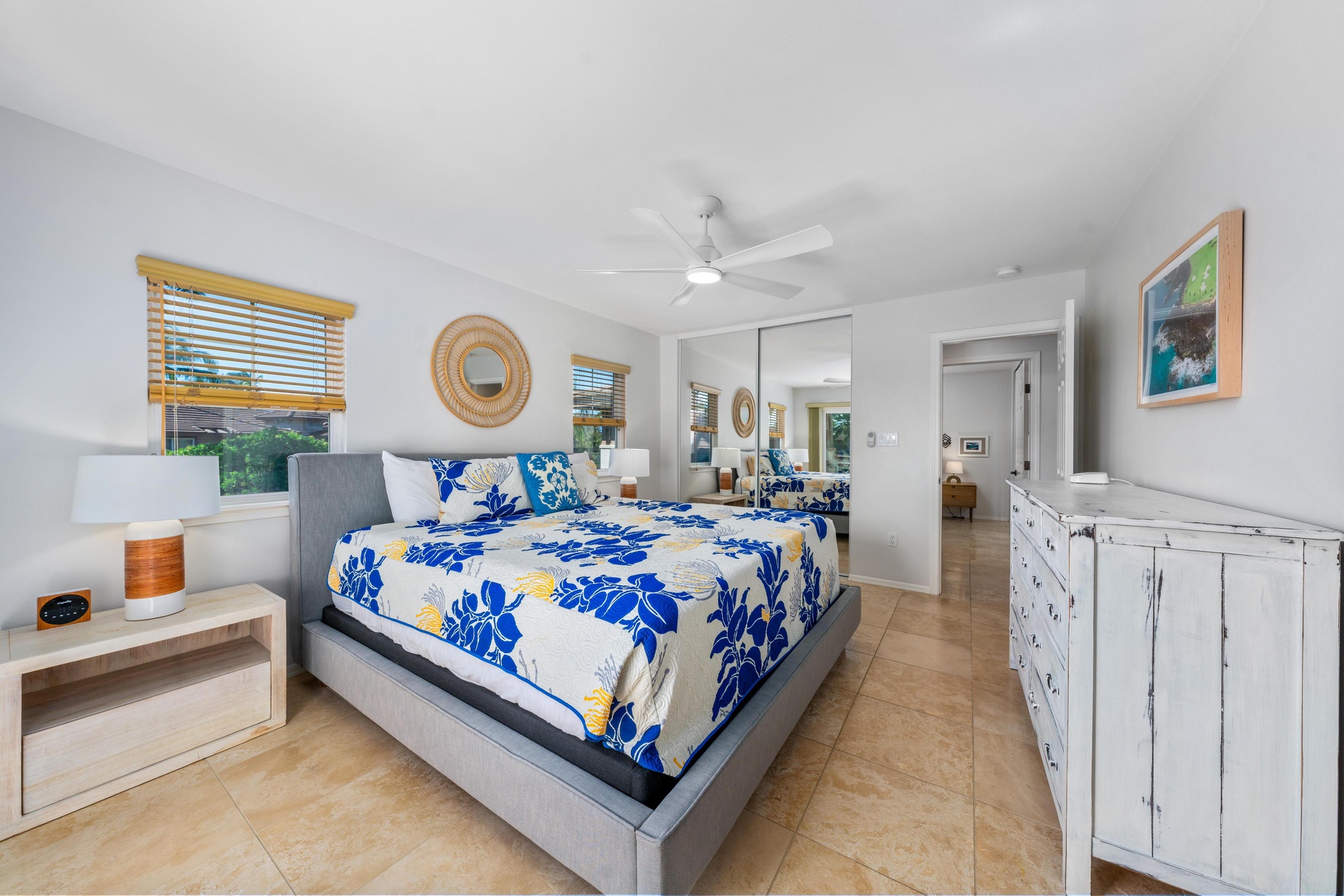 Your spacious bedroom features vibrant tropical bedding, natural wood blinds, and coastal decor that creates a perfect beachside retreat.