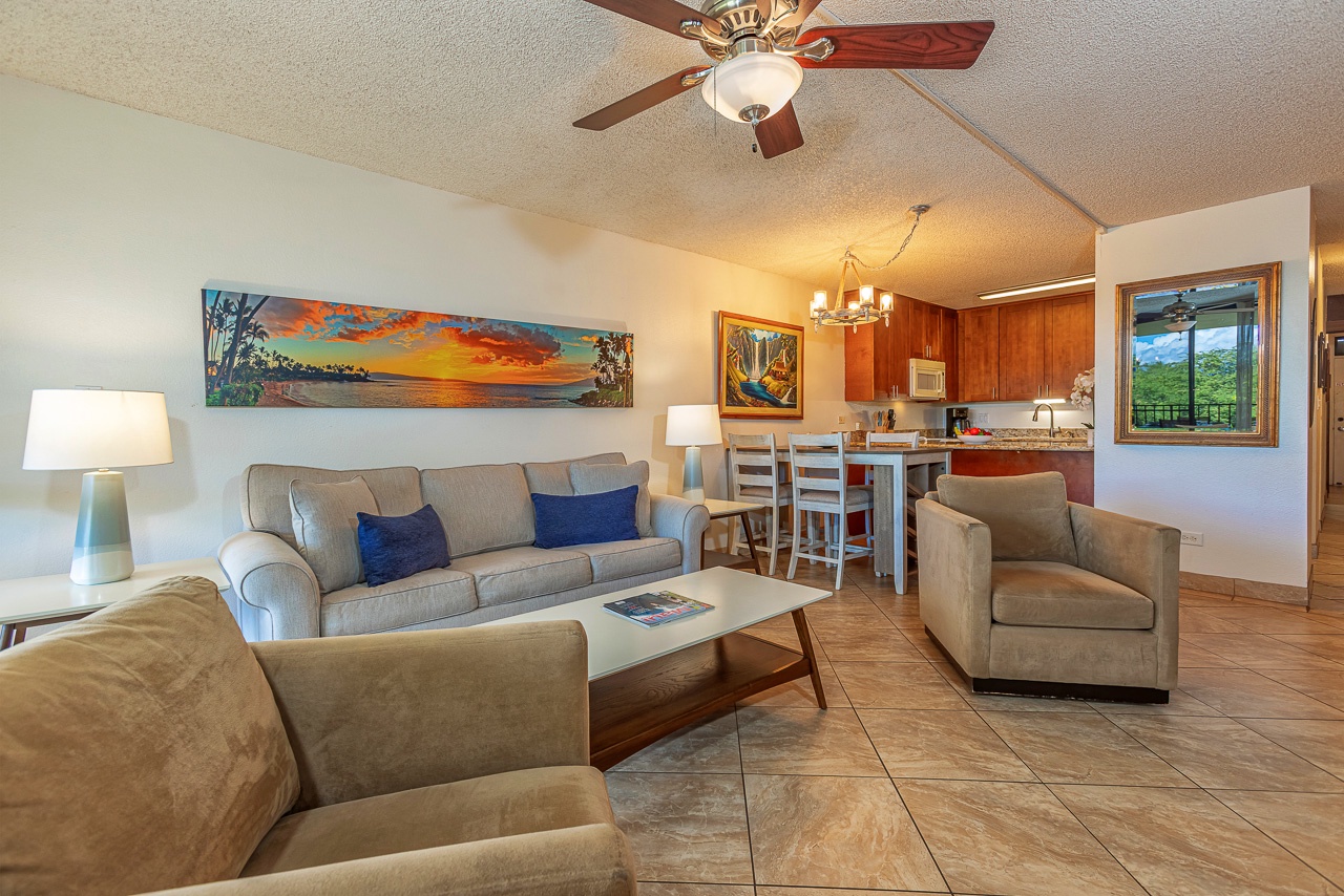Step into your open-concept retreat where the living room flows seamlessly into a fully equipped kitchen. Relax on plush seating, enjoy your morning coffee, and take in lush green views through the windows.