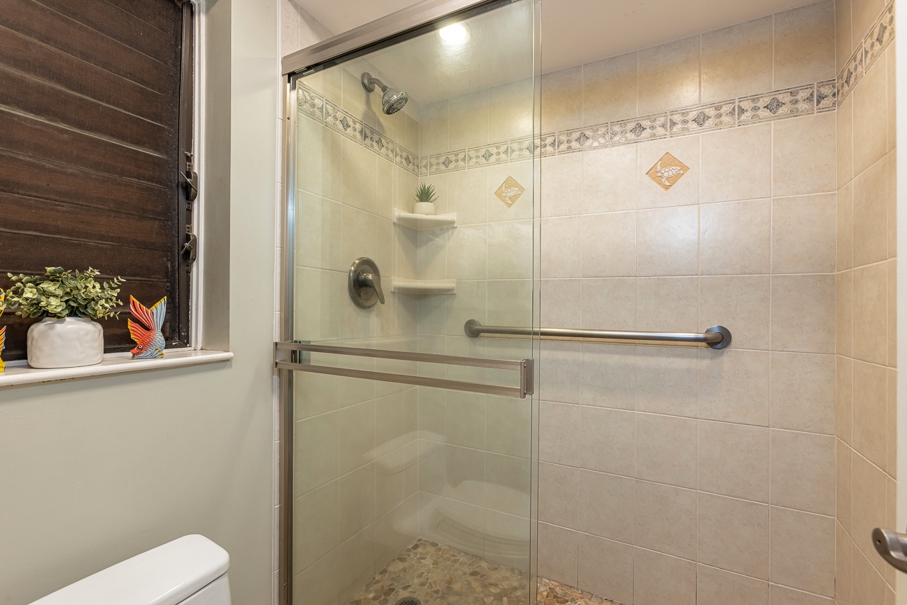 Step into a spacious, beautifully tiled walk-in shower with a convenient grab bar for added safety. The elegant tile work and built-in shelves make this your personal spa retreat.