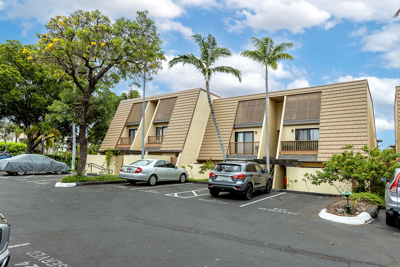 A distinctive two-story building with striking architectural design, featuring palm trees and convenient parking spaces for easy arrival access.