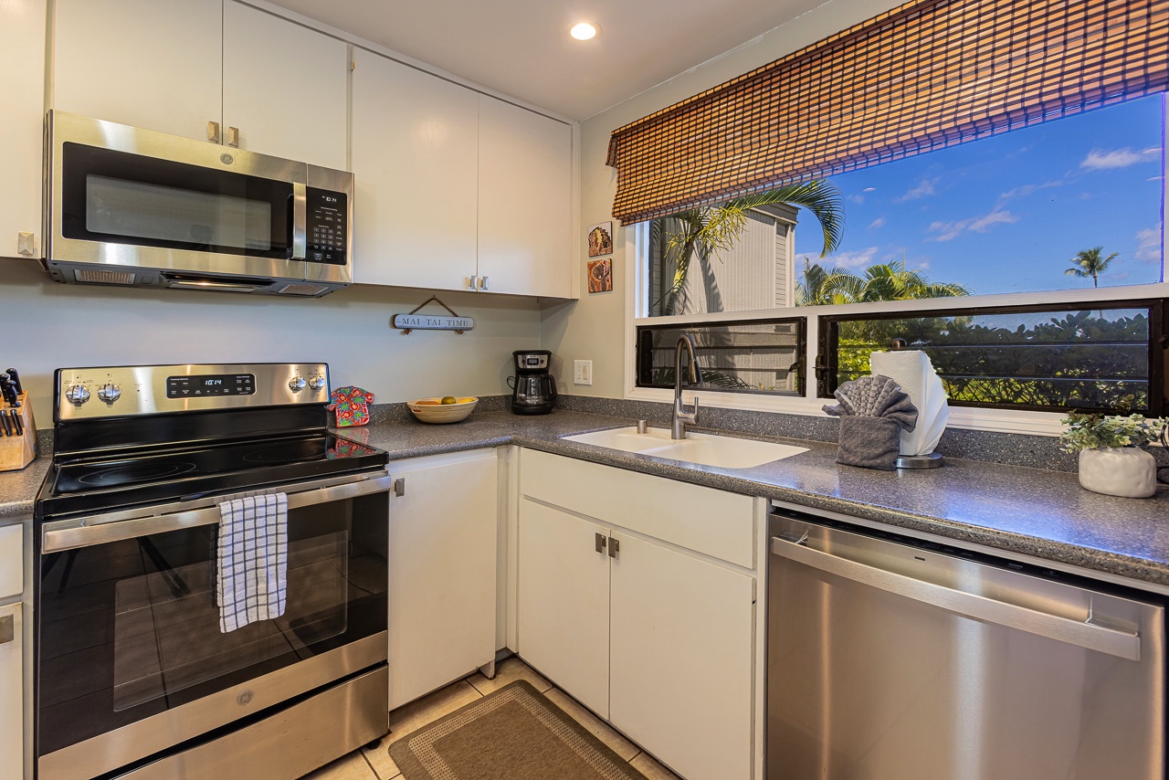 Your fully equipped kitchen features modern appliances and a bright window overlooking swaying palms and tropical gardens, making meal prep feel like a vacation in itself.