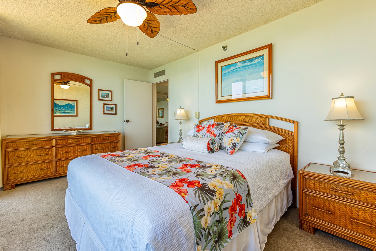 Your island-inspired bedroom awaits, with tropical ceiling fan, woven rattan furniture, and colorful floral accents that bring the spirit of the islands right to your door.