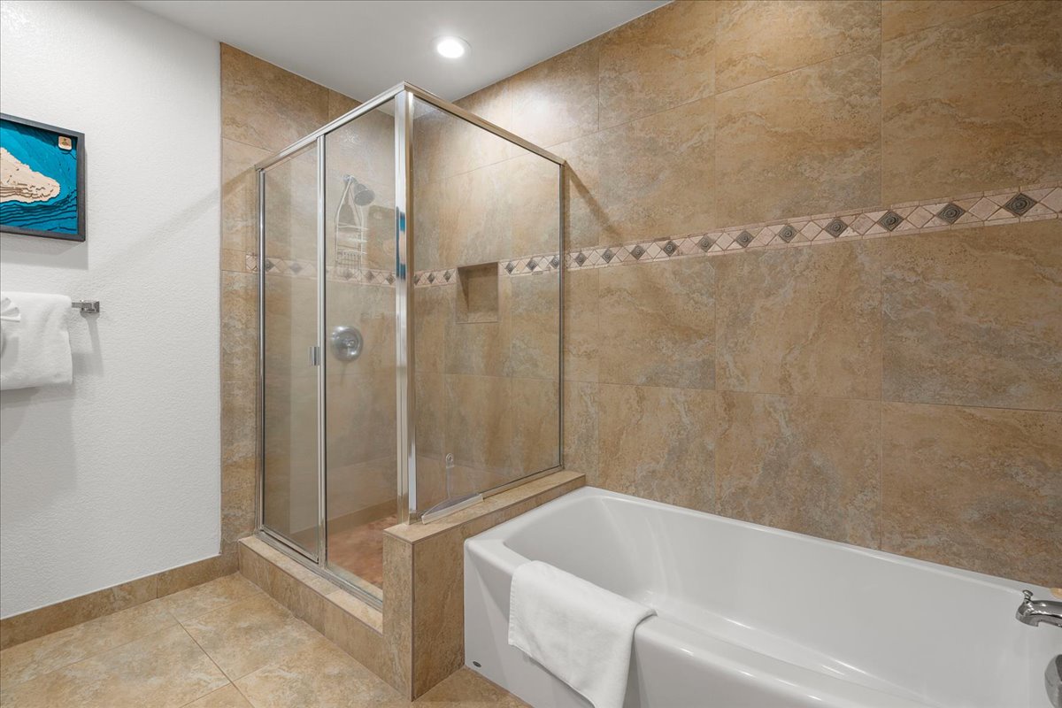 Indulge in your private spa-like bathroom featuring a walk-in shower and soaking tub, all wrapped in warm, elegant tile and fresh towels ready for your arrival.