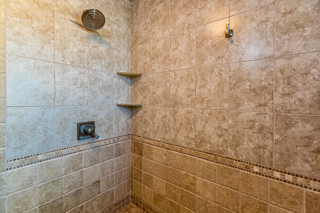 Step into your spacious tiled shower with rainfall showerhead, built-in shelves, and elegant mosaic accents—designed for your ultimate relaxation and refreshment.