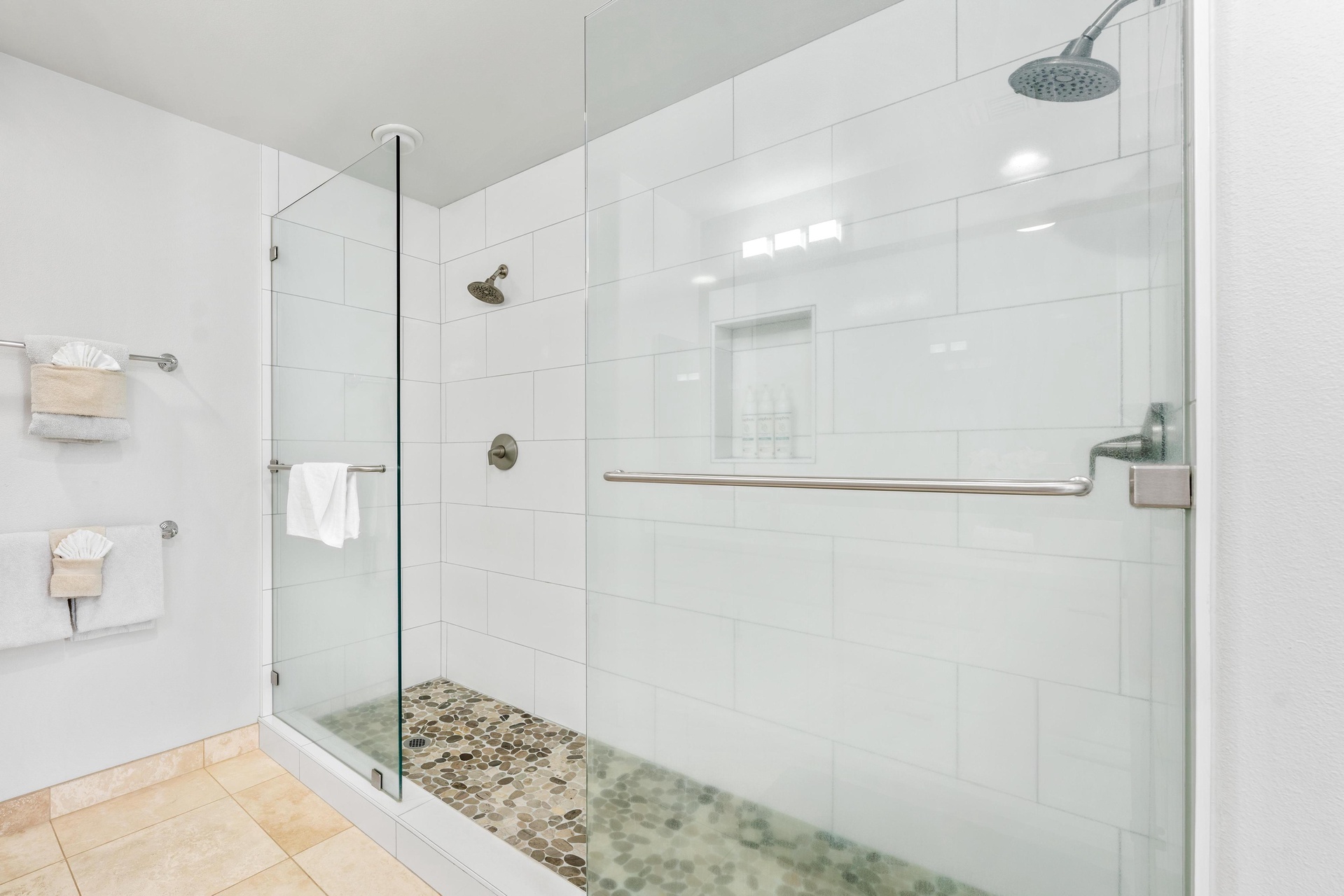 Step into your spa-like glass-enclosed shower with dual rainfall heads and natural stone flooring.