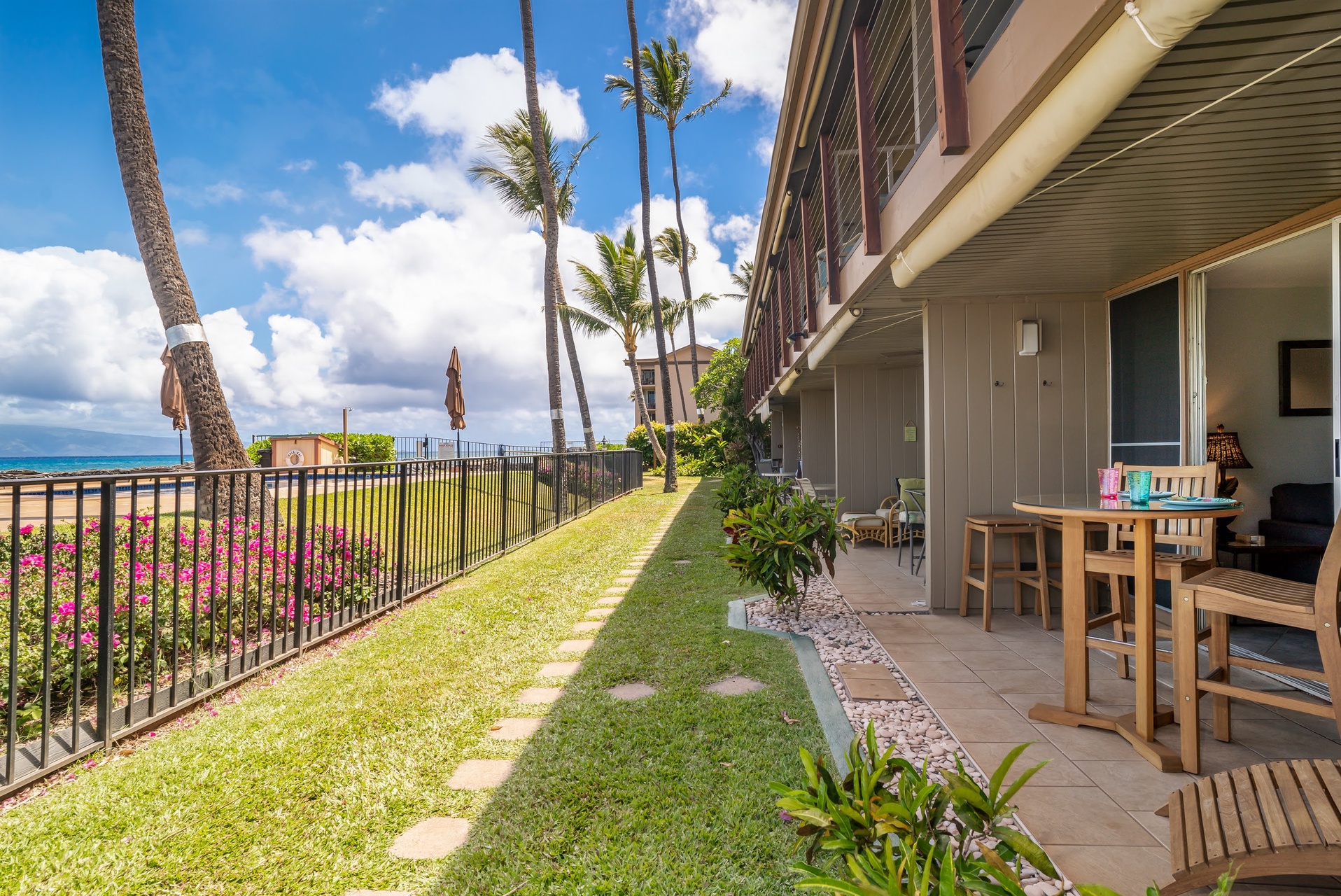 Beachfront property featuring a private patio area with ocean views, tropical landscaping, and convenient ground-level access.