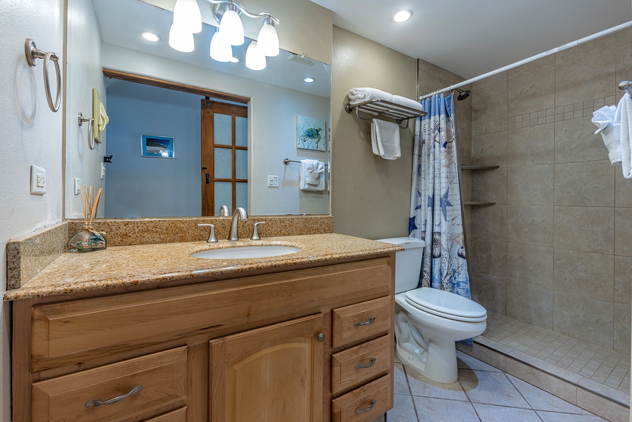 Your spacious bathroom features a granite vanity, walk-in shower with fresh towels, and coastal decor touches that invite you to unwind after a day of adventure.