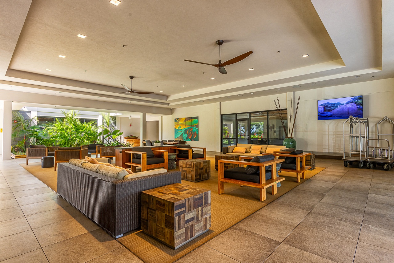 The spacious lobby welcomes you with natural light, stylish wood furnishings, and lush tropical greenery just beyond the open-air design.