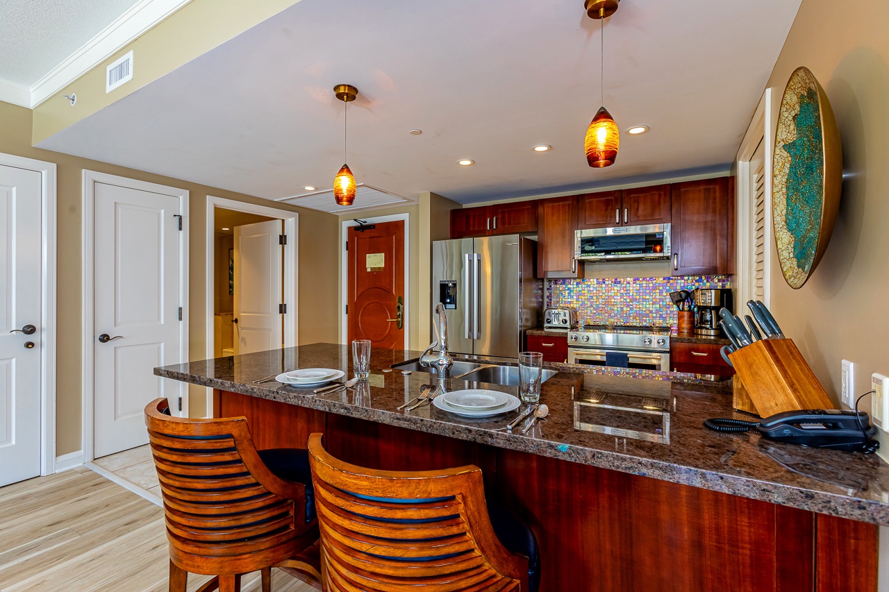 Beautifully appointed kitchen with rich wood cabinetry, colorful tile backsplash, and spacious counter with bar seating—perfect for cooking and entertaining during your stay.