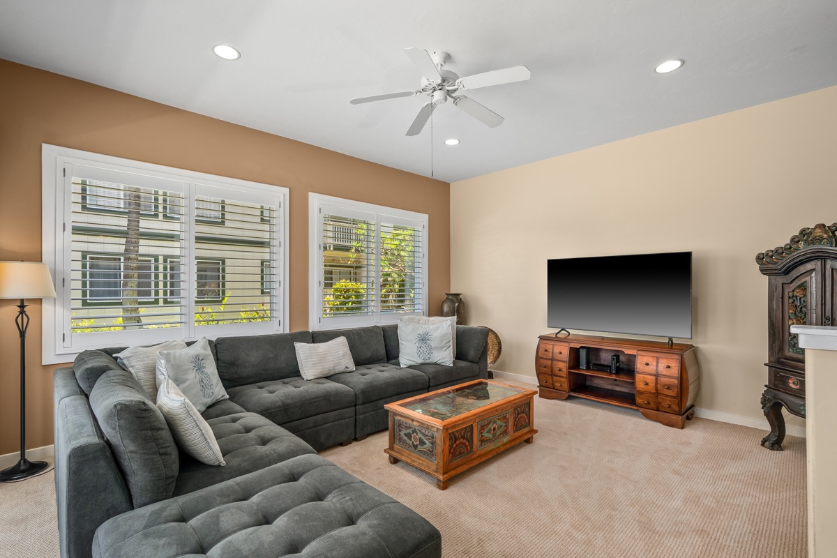 Sink into the plush sectional and unwind in your spacious living room, complete with modern entertainment setup and peaceful neighborhood views.