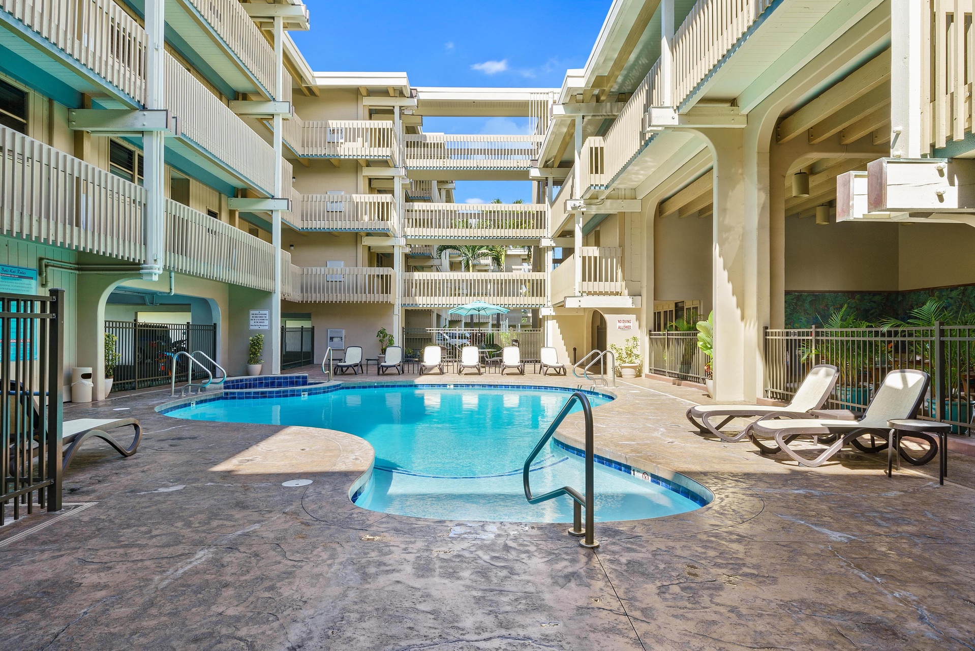 Dive into relaxation at your private courtyard pool, where sun loungers and shaded seating areas await beneath bright blue skies and swaying palms.