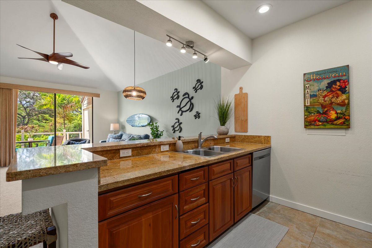 Step into your open kitchen featuring granite countertops, stainless appliances, and tropical garden views. Vaulted ceilings and island seating create a welcoming space for cooking and gathering.