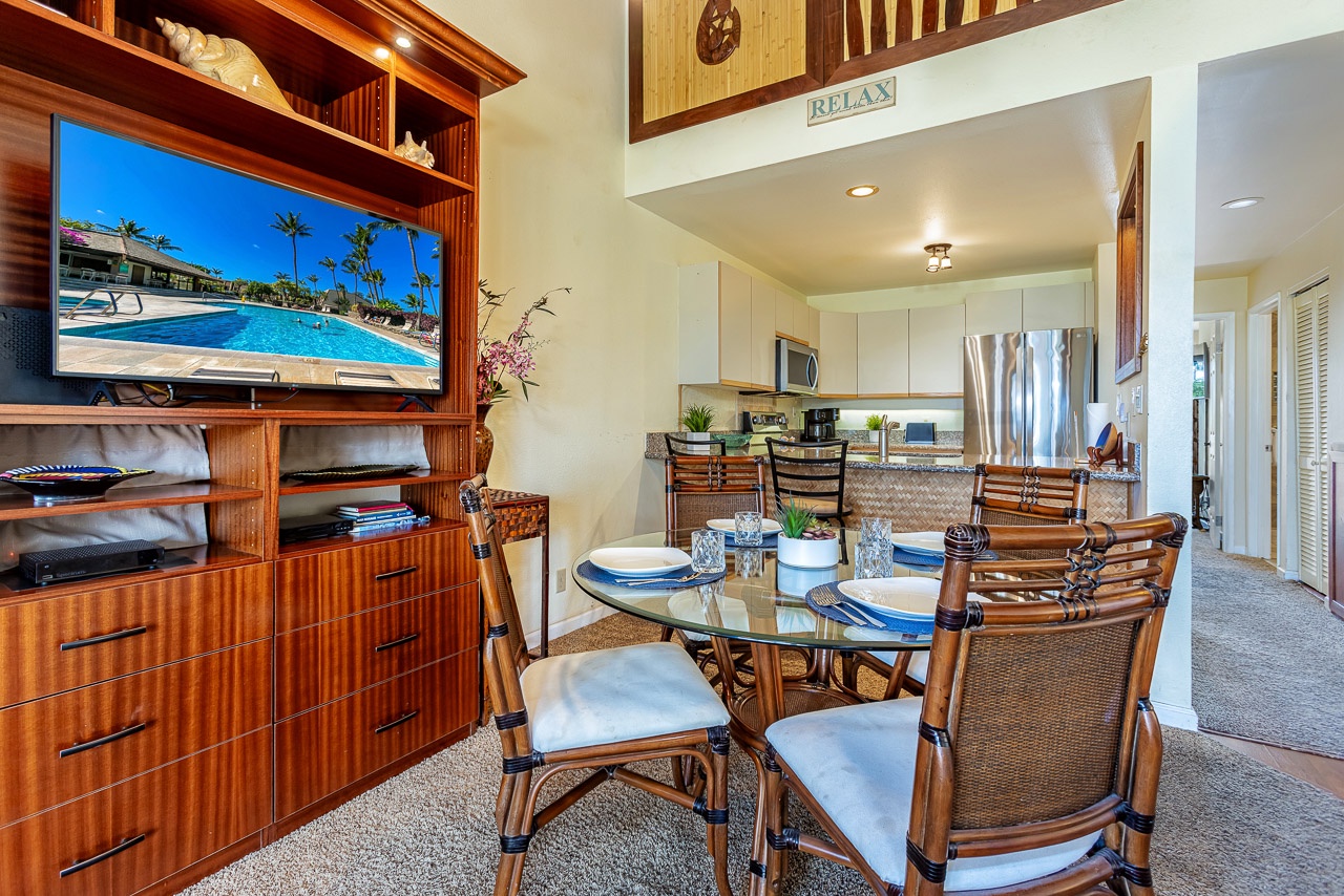 A bright, open-concept space invites you to unwind. Gather around the glass dining table for meals, then relax in the adjoining living area with tropical décor and a fully equipped kitchen nearby.