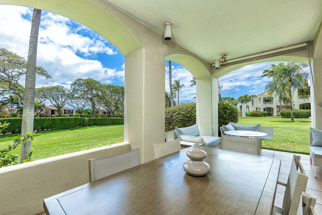 Covered outdoor dining and lounge space with elegant arched columns framing views of manicured tropical grounds and swaying palms—your perfect spot for morning coffee or evening gatherings.