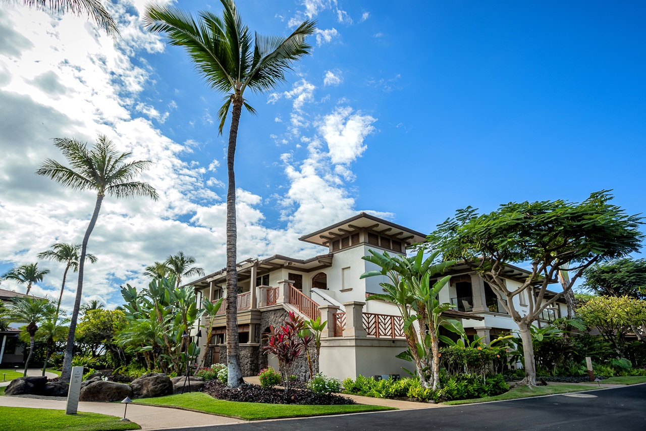A stunning tropical property framed by swaying palms and lush gardens, welcoming you to your island retreat under bright blue skies.