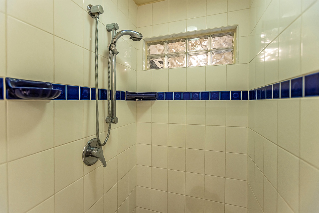 Step into your private tiled shower with adjustable showerhead and elegant blue accent trim for a refreshing start to your day.