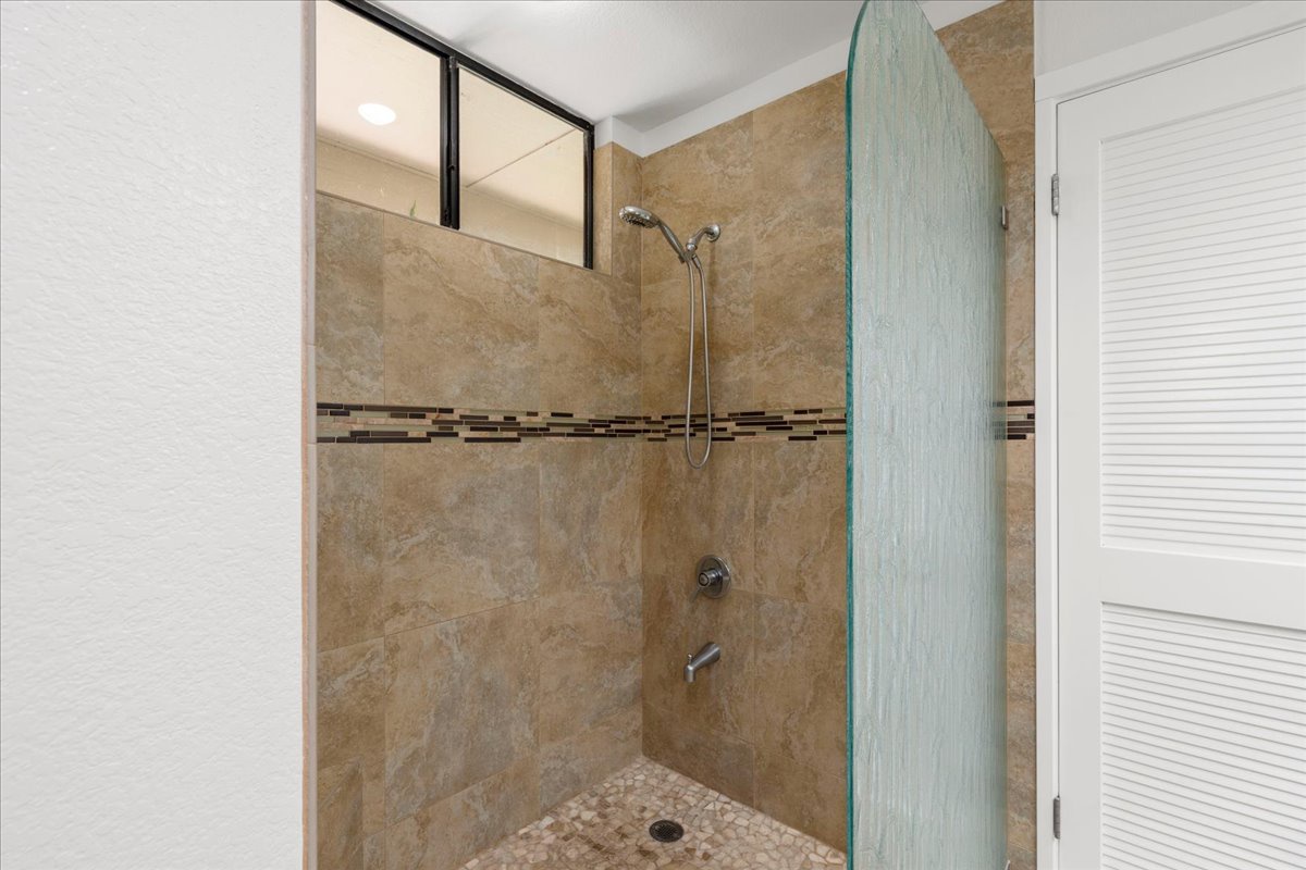 Step into your private walk-in shower with stylish tile work, a decorative mosaic accent band, and a modern glass enclosure that invites you to unwind.