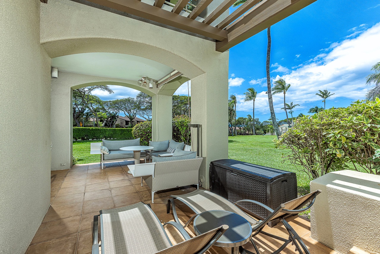 Your private covered patio invites you to unwind with comfortable seating overlooking lush green lawns and swaying palms under endless tropical skies.