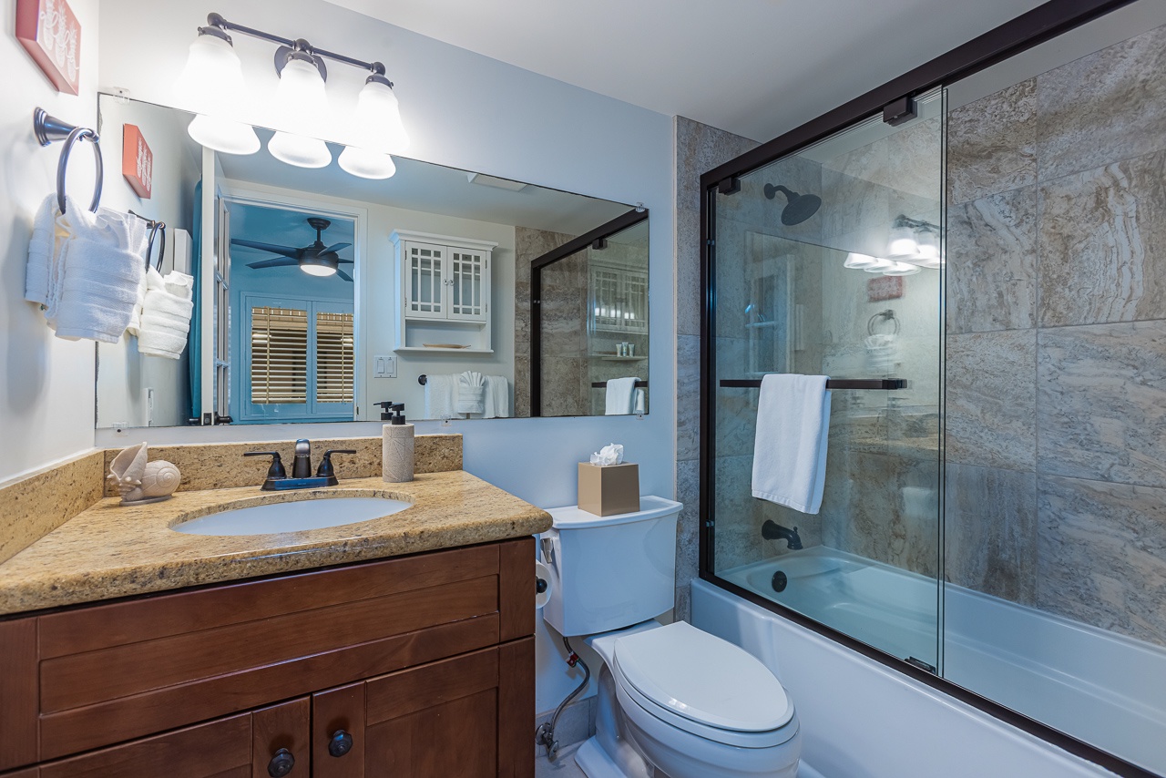 Step into your spa-like bathroom featuring elegant stone tiling, a spacious glass-enclosed tub, and luxurious amenities for ultimate relaxation.
