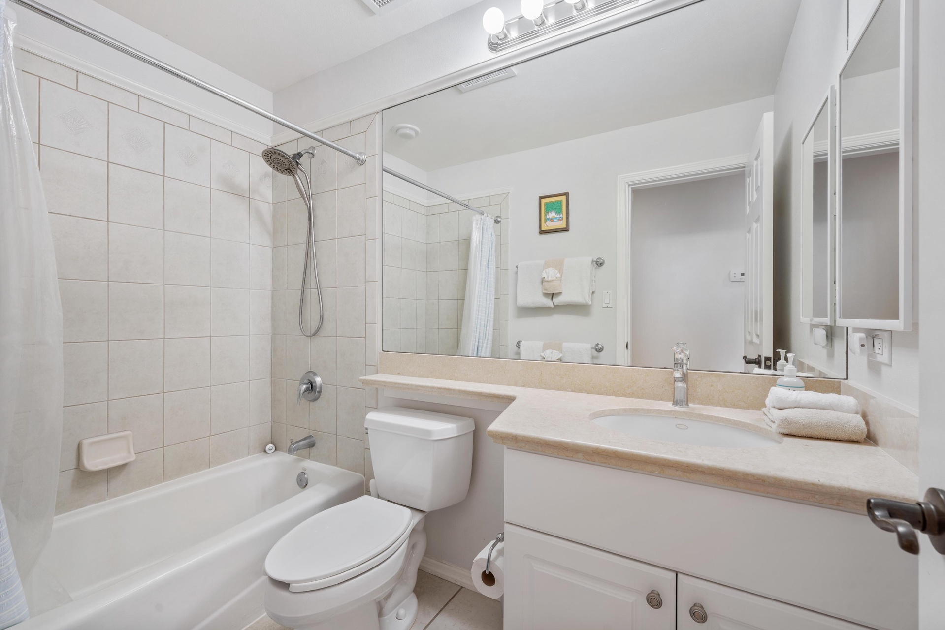 Step into your pristine bathroom featuring a relaxing tub, spacious vanity, and fresh towels waiting for your arrival.