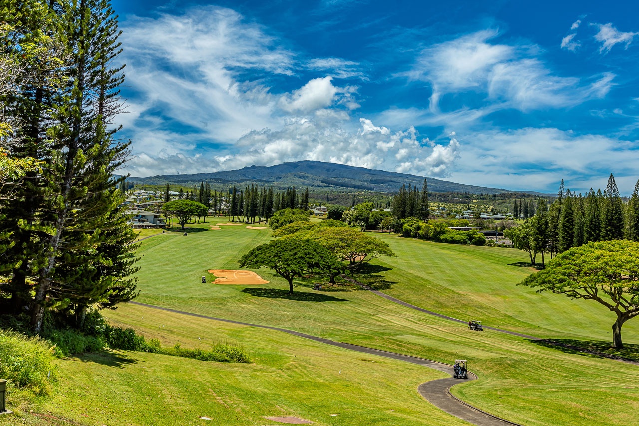 Championship golf course near property with lush fairways, mature trees, and mountain backdrop on a pristine day—perfect for golf enthusiasts seeking an island paradise retreat.