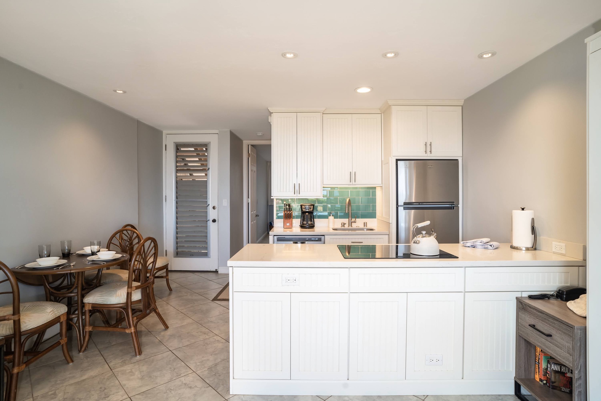 Fully equipped kitchen features modern appliances, a convenient countertop with storage, and a bright turquoise backsplash. The adjacent dining area invites you to enjoy meals in comfort.