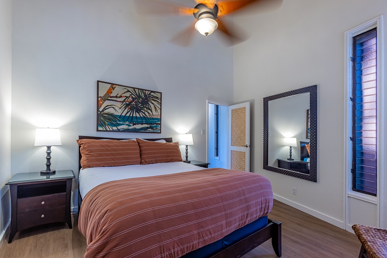 Unwind in this cozy bedroom featuring a plush bed, tropical artwork, and a warm color palette perfect for your restful retreat.