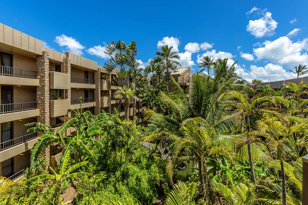 Lush tropical gardens surround the property, offering a peaceful, resort-style atmosphere beneath swaying palms and bright blue Hawaiian skies.