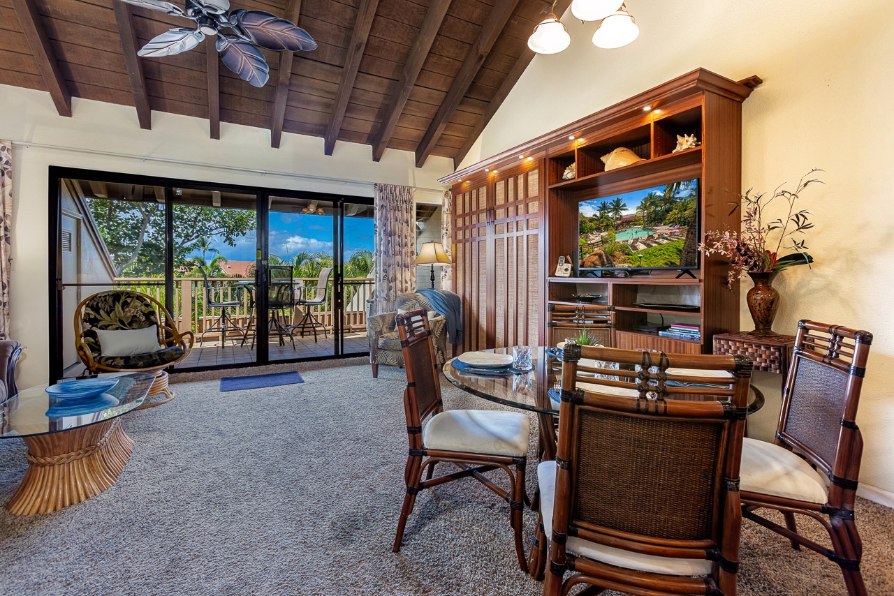 Settle into your inviting living space where warm wood accents and island-style charm blend beautifully. Through the glass doors, your private lanai opens to tropical greenery and blue skies—perfect for morning coffee or sunset drinks.