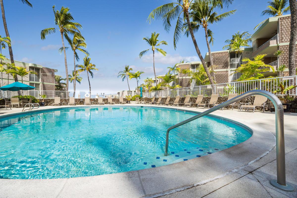 Sparkling pool surrounded by swaying palms and lounge chairs, perfect for soaking up the tropical sun during your Hawaiian getaway.