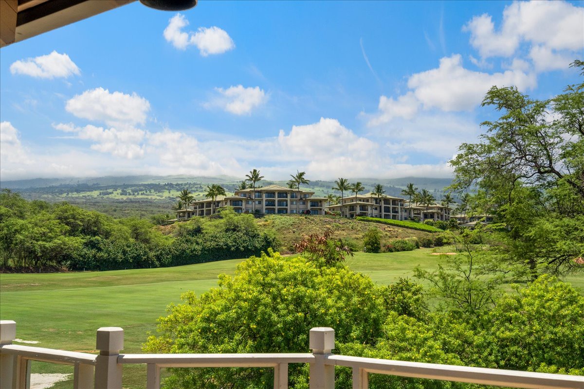 Expansive golf course views showcase lush fairways and manicured greens, with the property perched elegantly on a hillside amid tropical palms, rolling mountains, and blue skies beyond.