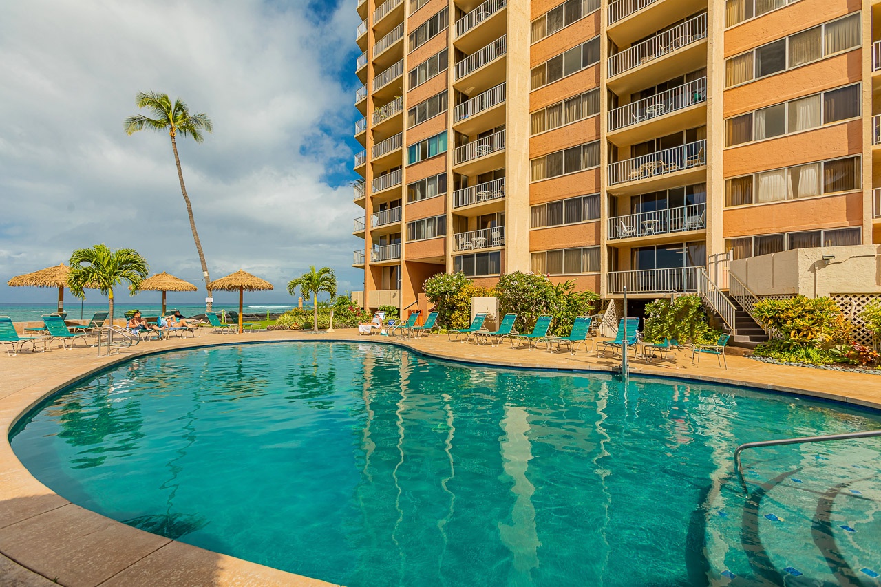 This beachfront property features a sparkling pool with ocean views, palm trees swaying in the breeze, and lounge chairs waiting for you.