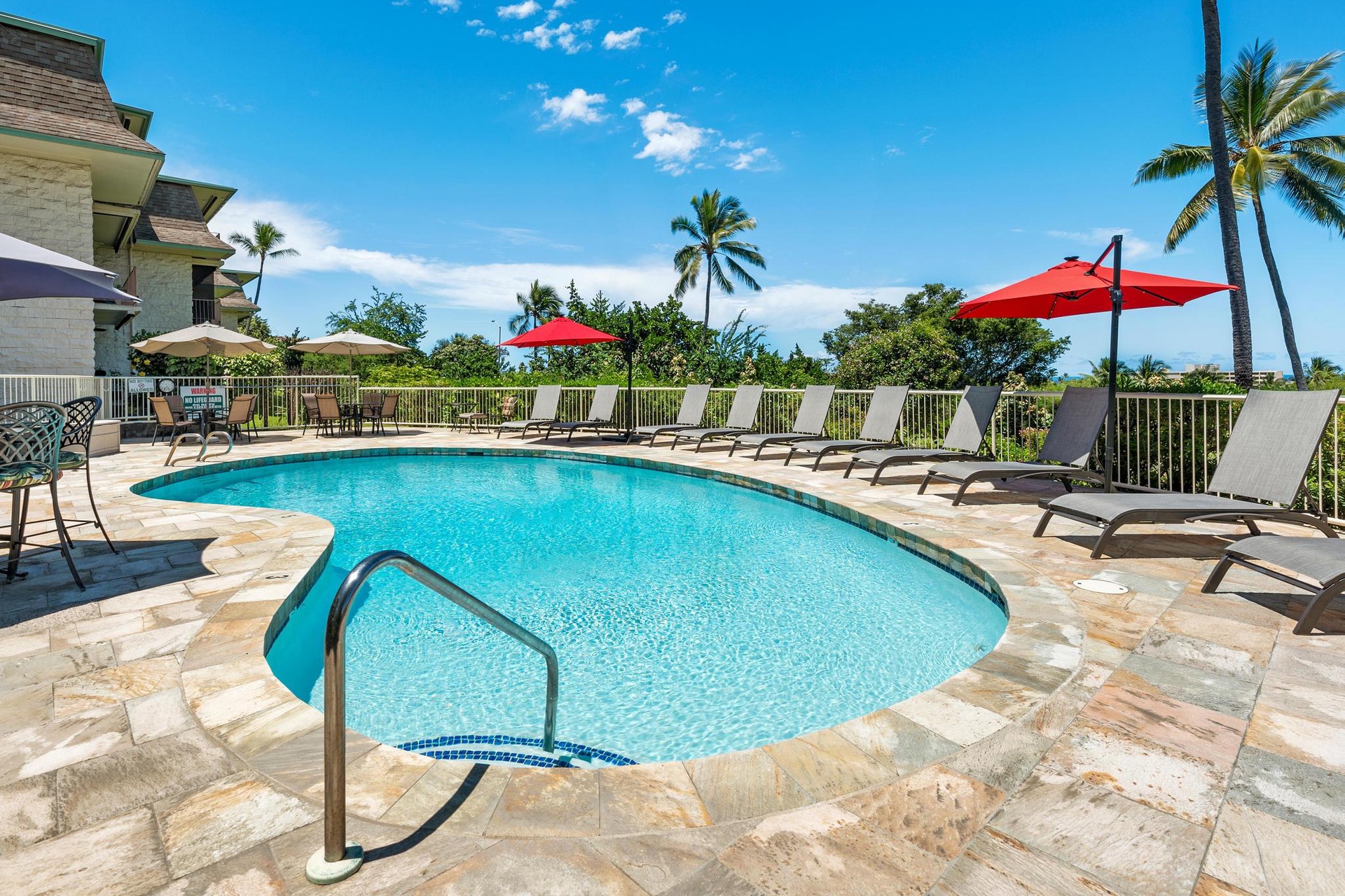 Dive into your own tropical oasis with crystal-clear waters, comfortable loungers, and vibrant red umbrellas framing paradise views.