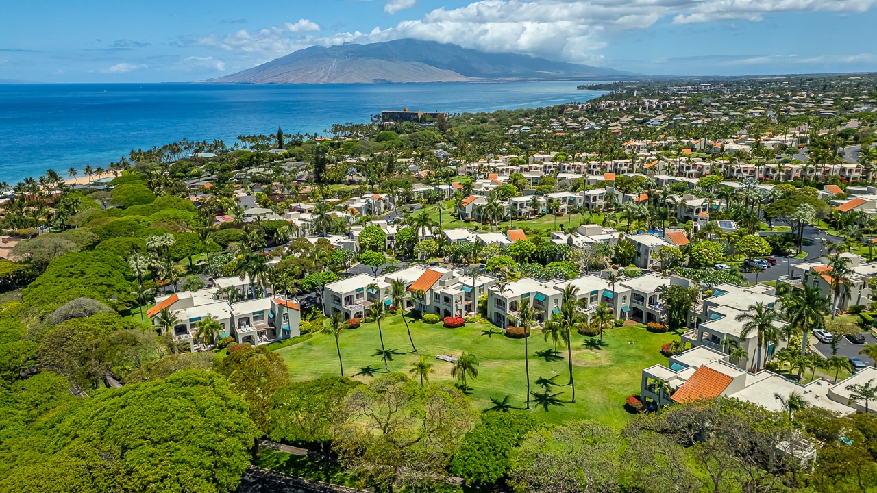 Aerial view of a coastal resort community featuring tropical landscaping, beachfront access, and mountain vistas across turquoise waters.