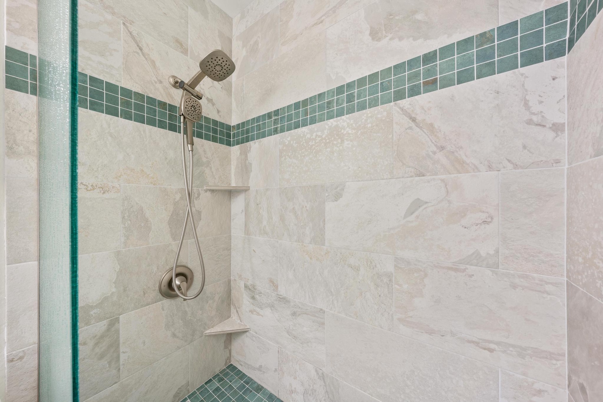 Step into your spa-like shower with elegant marble tiles and soothing turquoise accents for a refreshing start to each day.