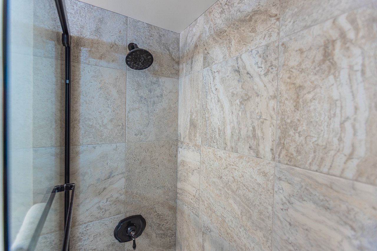 Step into your private marble sanctuary with rainfall shower and elegant fixtures for pure relaxation.