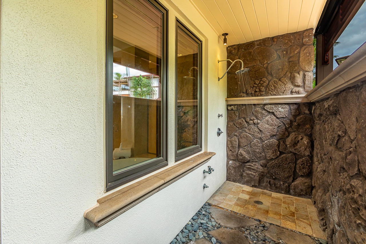 An outdoor shower awaits beneath a sheltered overhang, featuring natural stone walls and polished stone flooring—a tranquil spot to rinse off after your day's adventures.