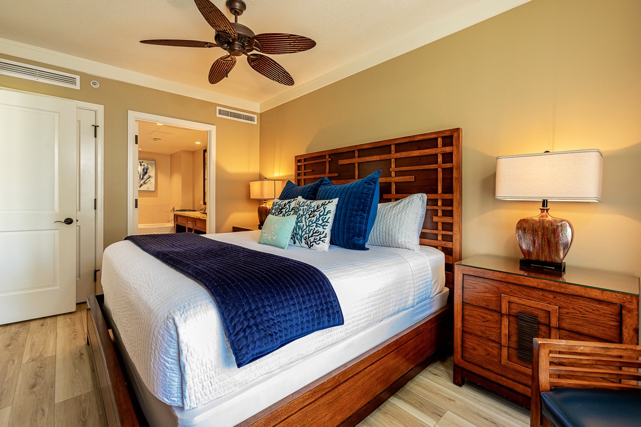 Sink into plush linens and tropical-inspired décor in your serene bedroom retreat, where rich wood tones and breezy ceiling fan create your own island escape.