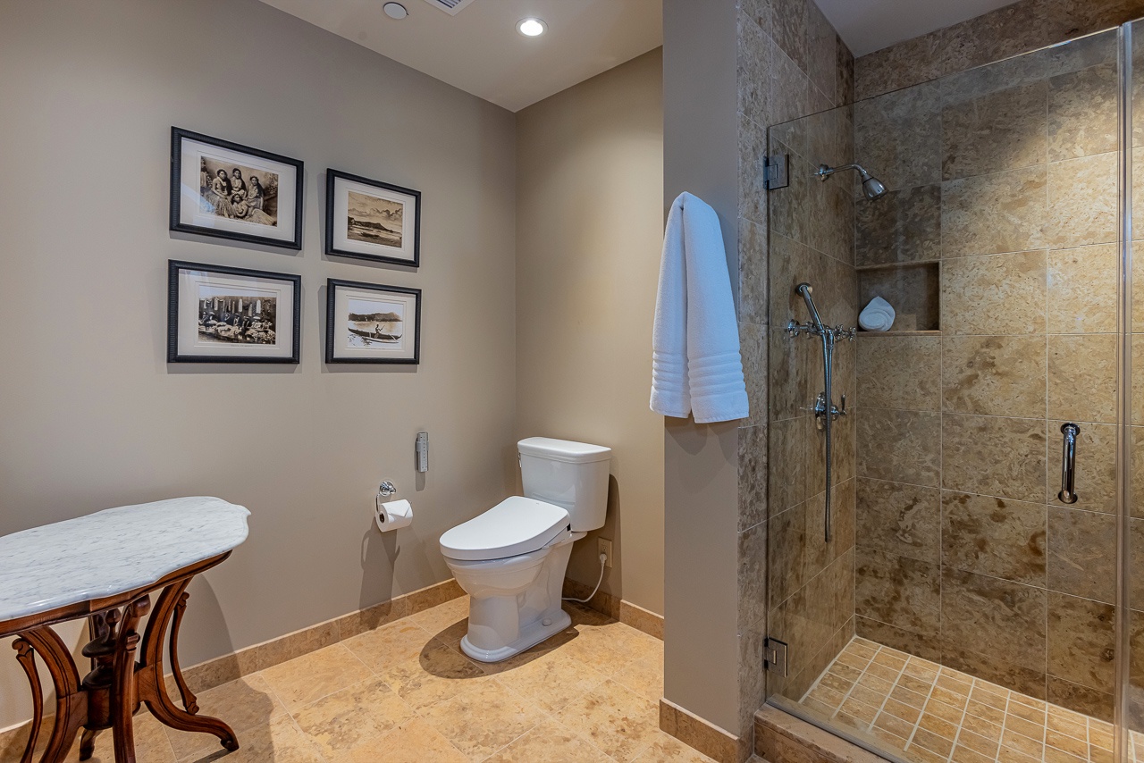 Step into your private bathroom with elegant stone tile and a spacious walk-in shower. Fluffy towels await, ready to wrap you in comfort after a refreshing rinse.