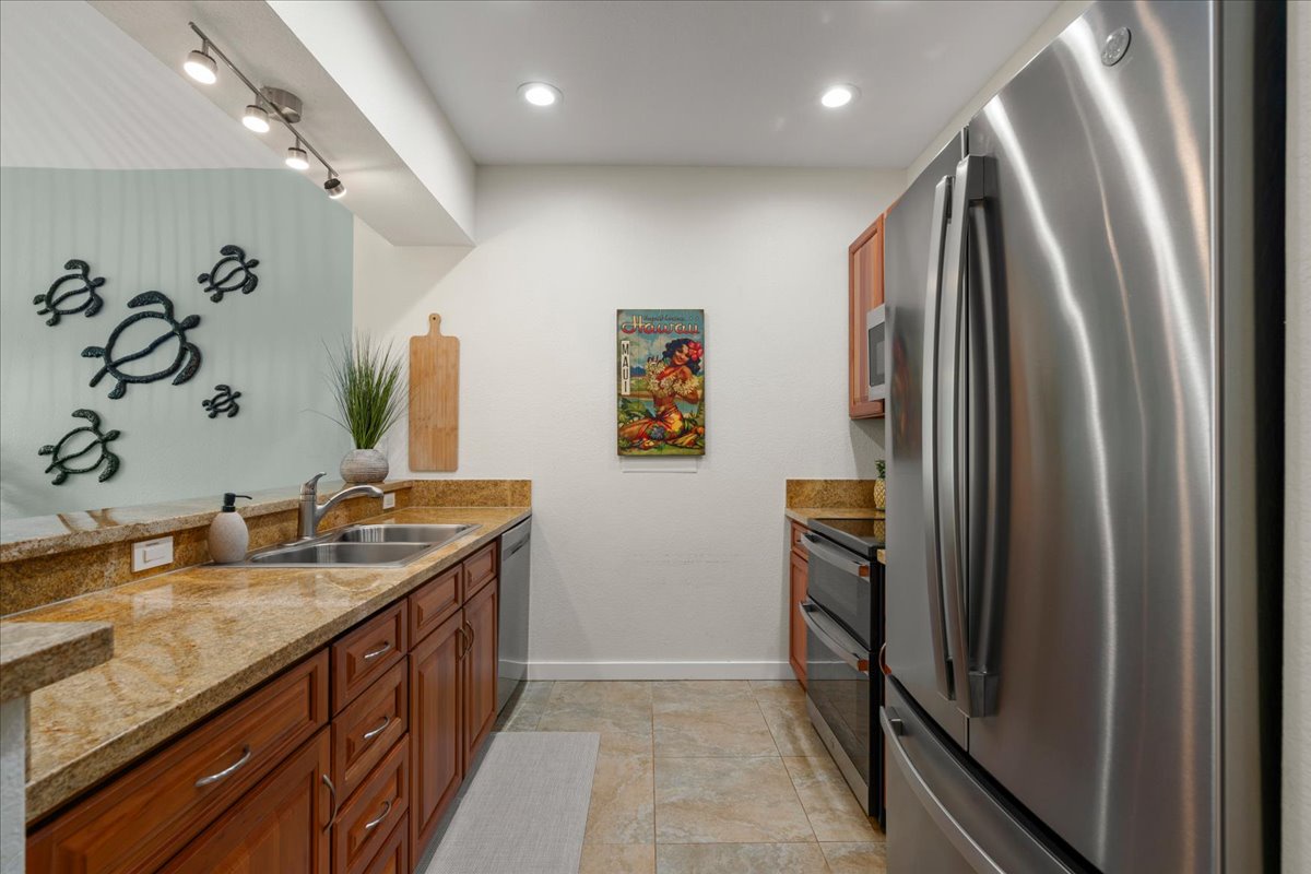 Your fully equipped kitchen features modern stainless-steel appliances and granite countertops, ready for you to prepare meals with coastal charm—note the playful sea turtle wall art.
