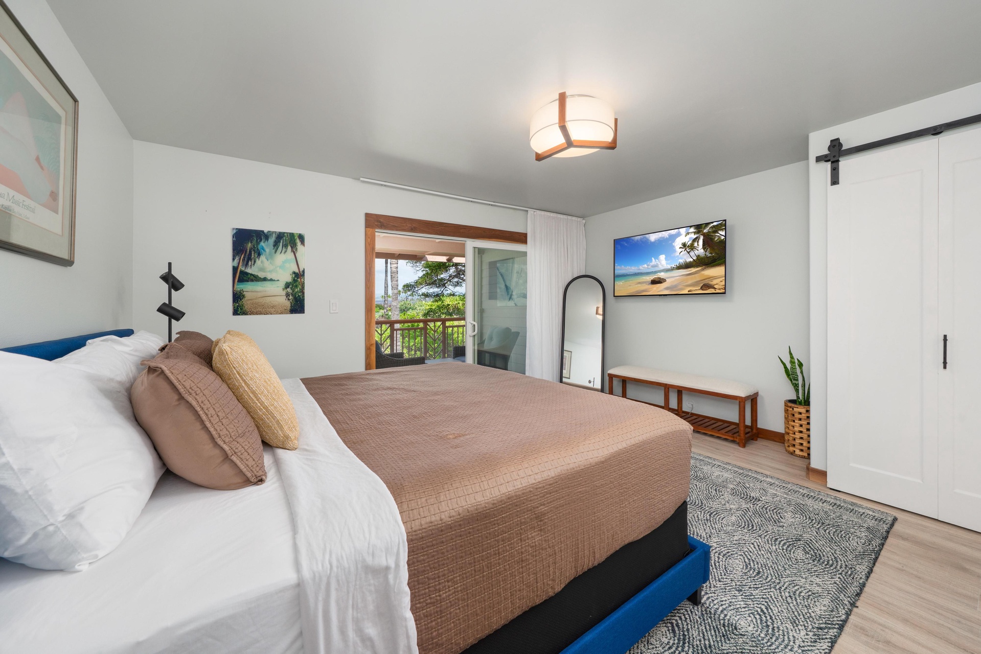 Wake up in your serene bedroom featuring tropical artwork, warm lighting, and a balcony showcasing lush greenery beyond.