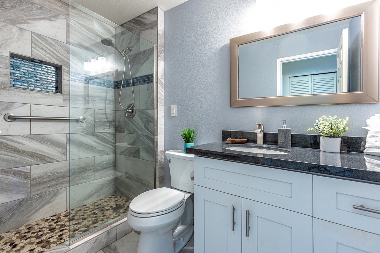 Step into your private spa-like retreat with sleek granite counters, a spacious walk-in shower with elegant tilework, and thoughtful touches like fresh greenery to welcome you.