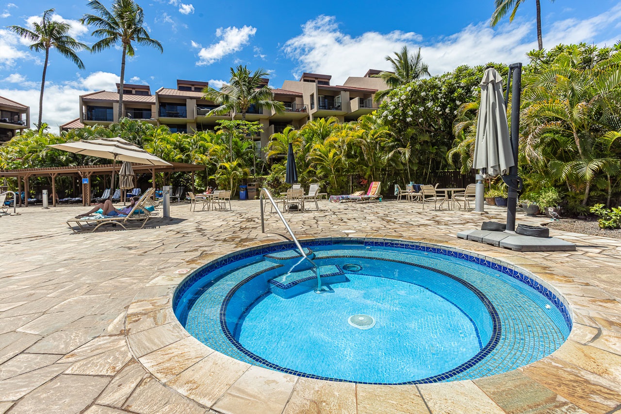 A tropical paradise awaits with a sparkling hot tub surrounded by lush palm gardens, lounge chairs, and shaded seating—your perfect spot to unwind under sunny skies.